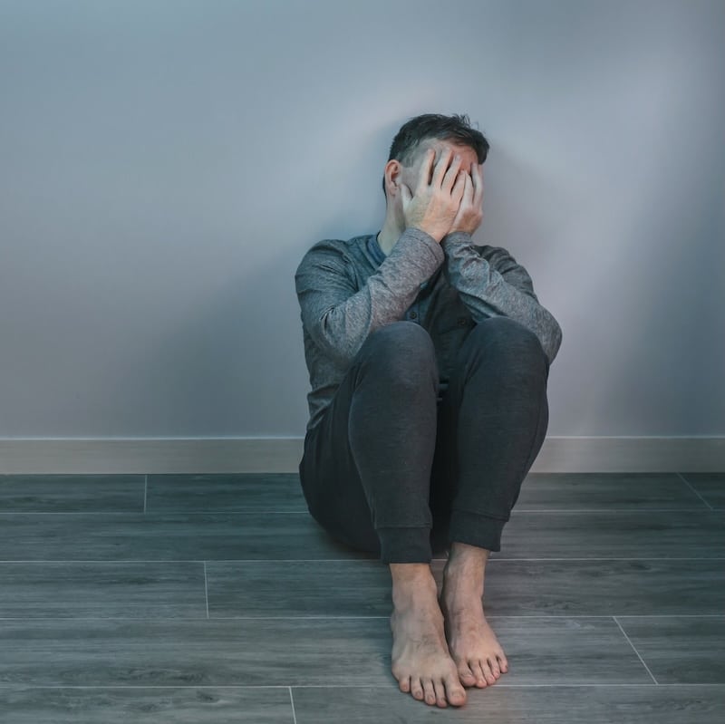 Man crying while covering his face with hands sitting on the floor Man crying while covering his face with hands sitting on the floor